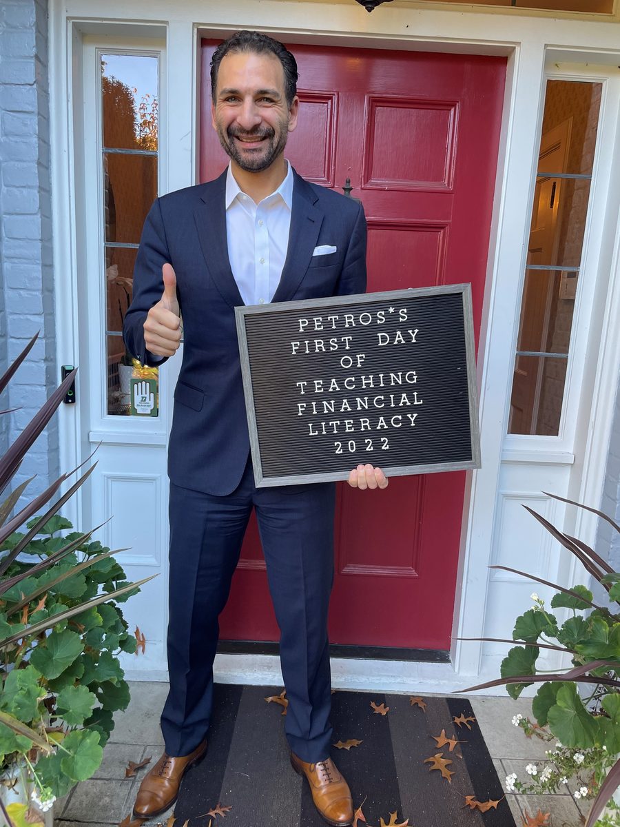 Petros holding a letterboard reading: Petros's first day of teaching financial literacy, 2022